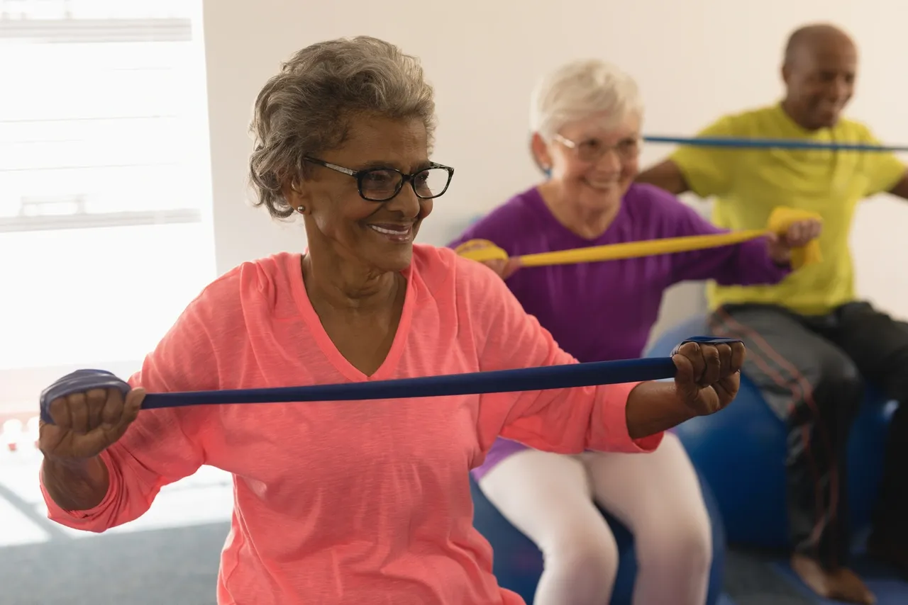 Two older women are doing exercises with a hula hoop.