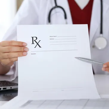 A person holding a pen and paper with a rx sign on it.