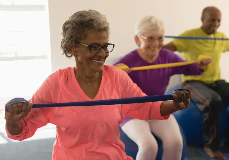 Two older women are doing exercises with a hula hoop.